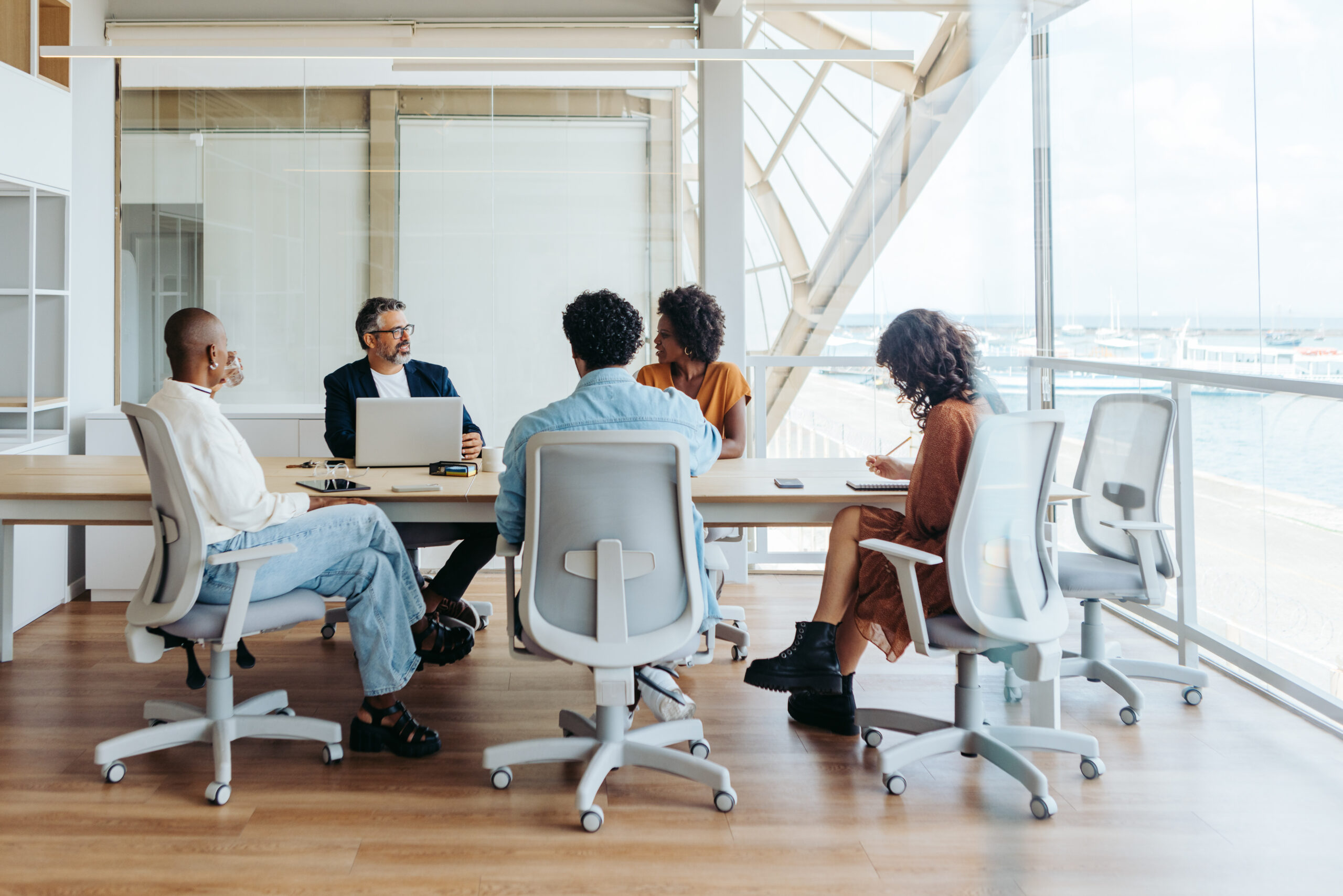 Diverse group of professionals collaborating and discussing ideas in a business meeting Business people collaborating in a modern office. They are engaged in a brainstorming session, discussing ideas and planning a project. The team demonstrates effective teamwork and emphasizes diversity and inclusion in the workplace.